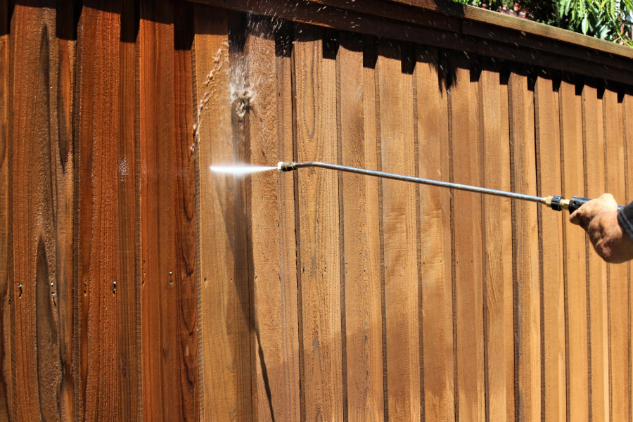 worker staining a wood fence